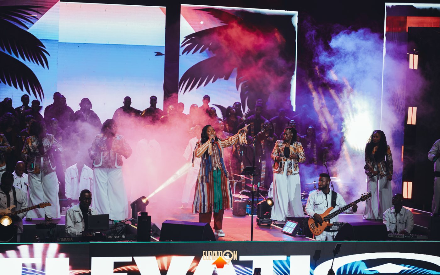 Clarisse Flambeau leading worship on stage with full choir and band